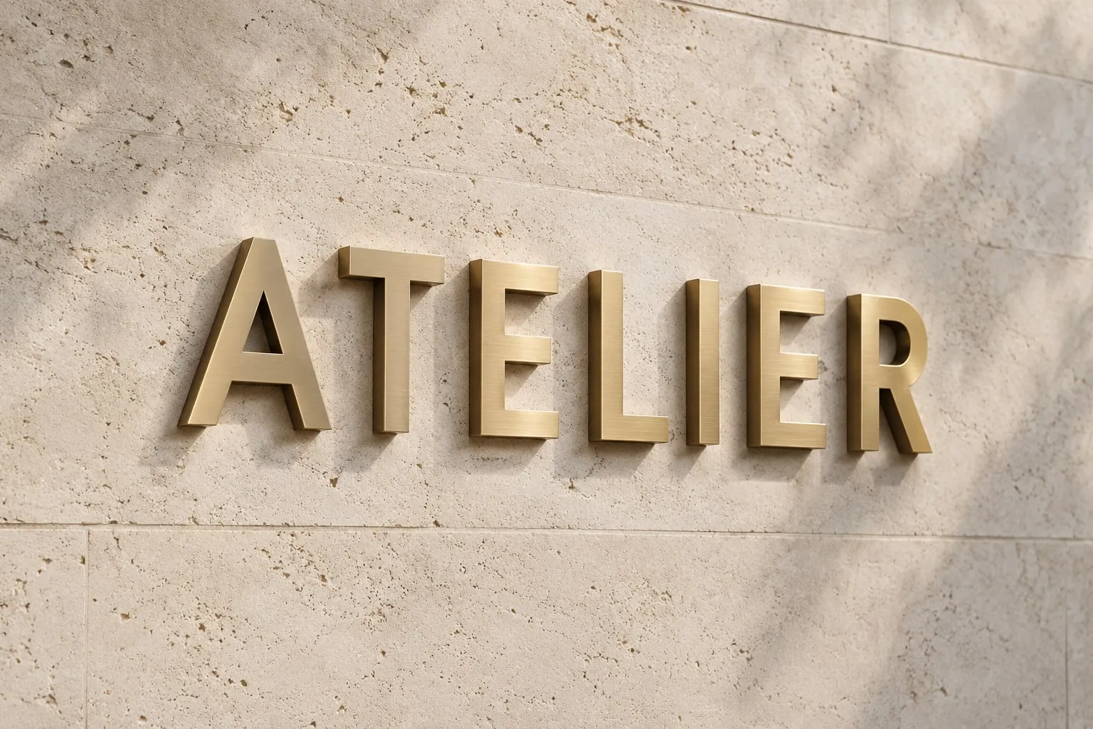 Brushed brass ATELIER letters mounted on limestone