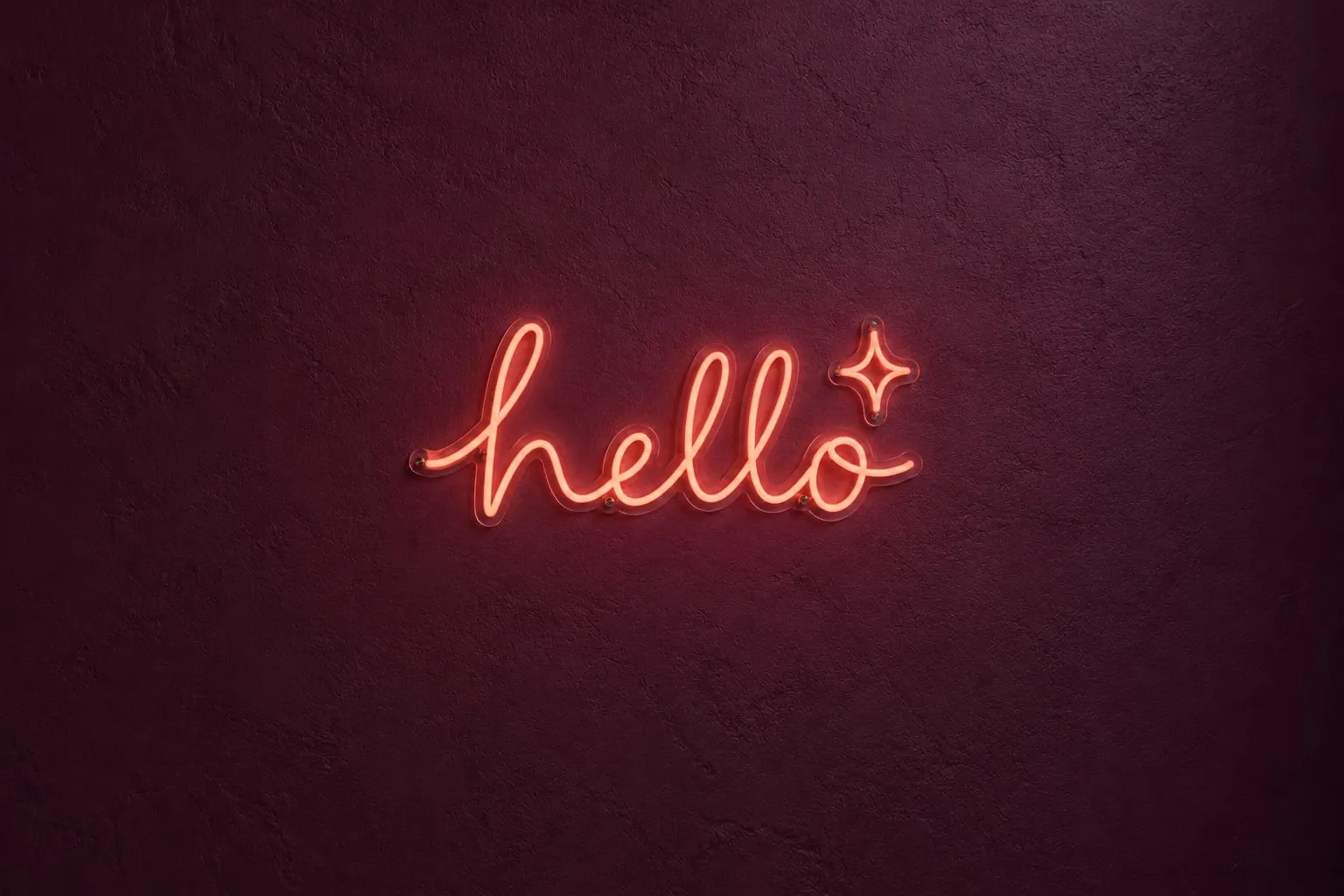 Coral hello LED neon sign with a sparkle on a plum wall